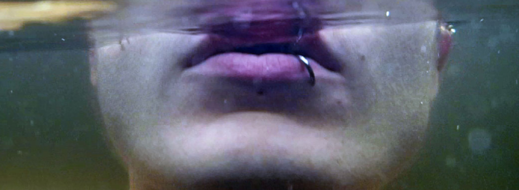 image of womans lips and jaw under water she has a lip piercing