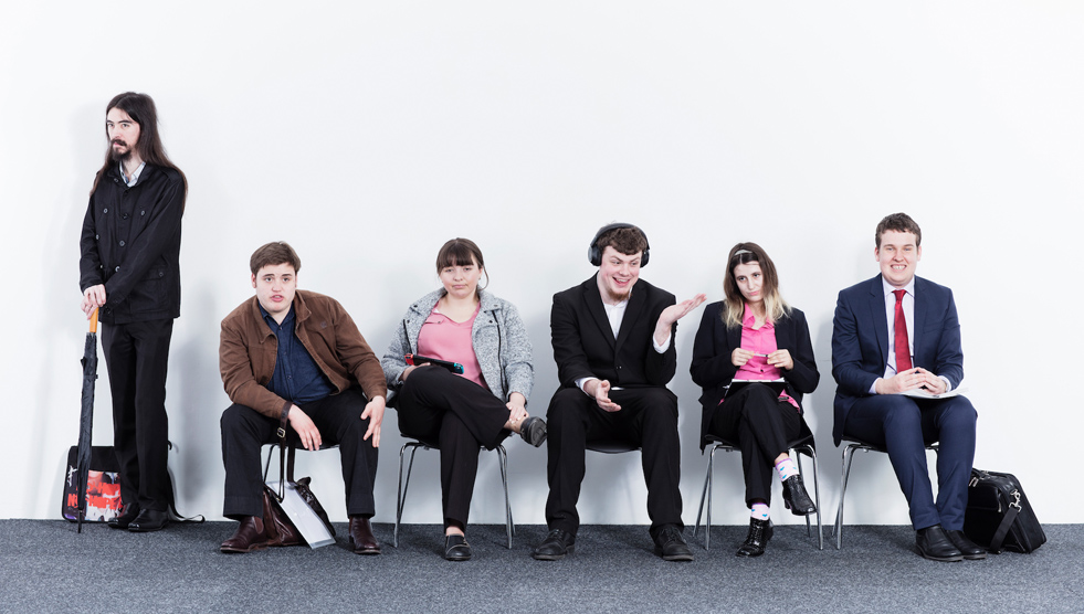 Employable Me: A group of young people are sitting and standing against a wall